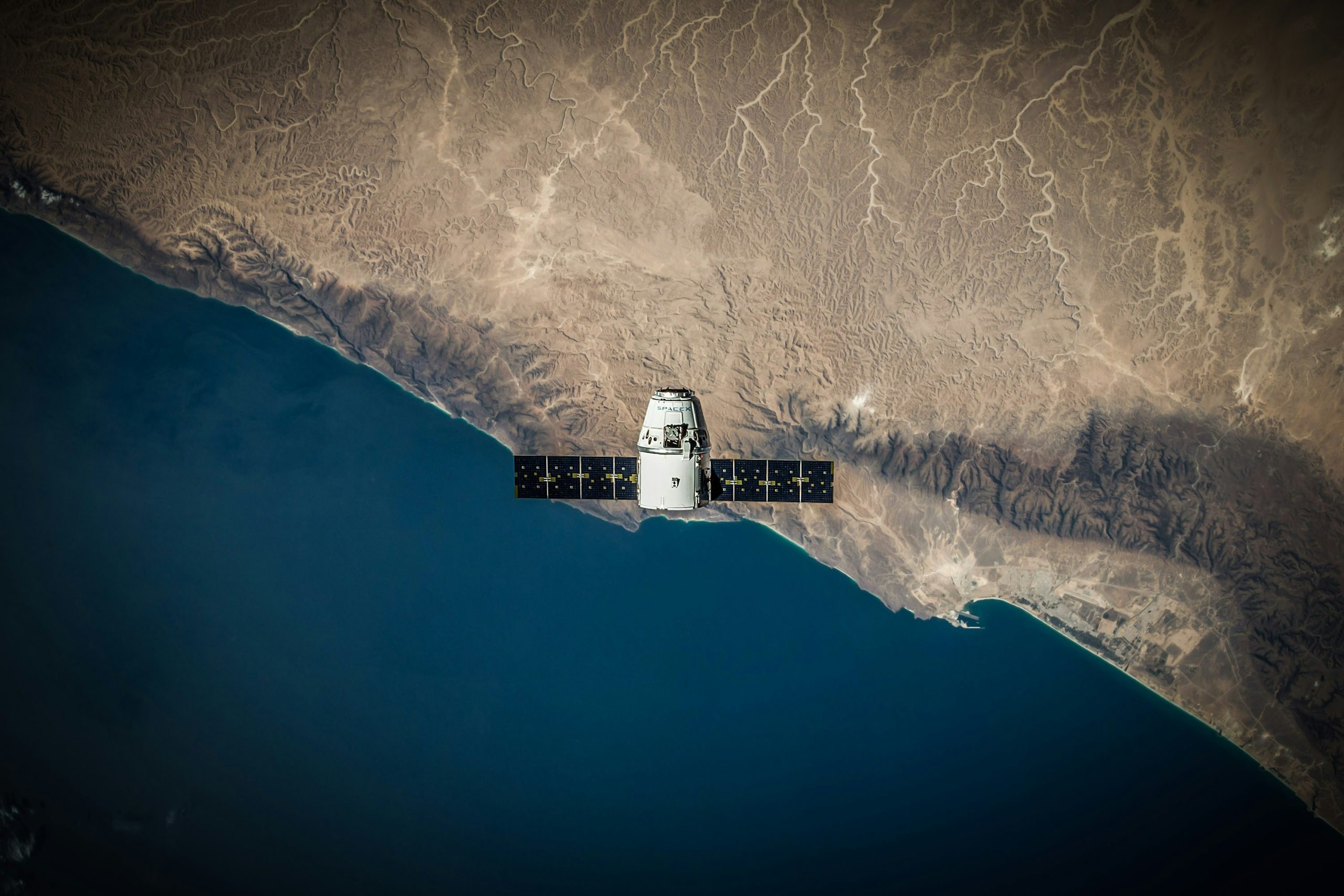 A satellite in orbit above Earth's coastline